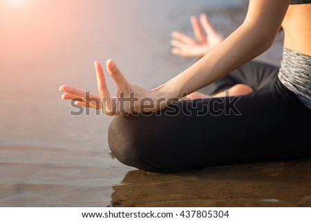 Close up of a woman\'s body and hands meditating and doing yoga at the beach,Asia young woman practicing yoga.