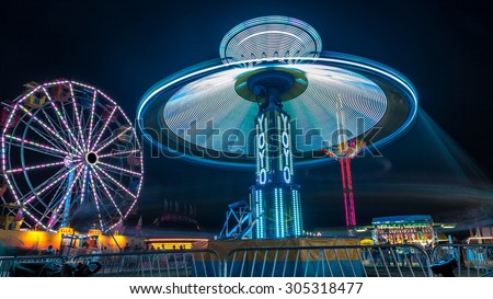 Giant Ferris Wheel and Yo-Yo amusement ride side by side in night time shot with long exposure.