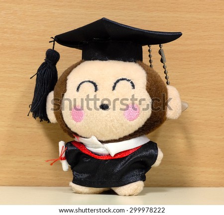 A graduation monkey plush doll with a wooden background.