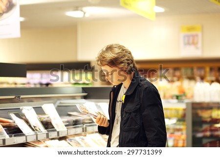 Man shopping in supermarket reading product information