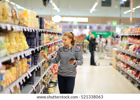Woman shopping in supermarket reading product information