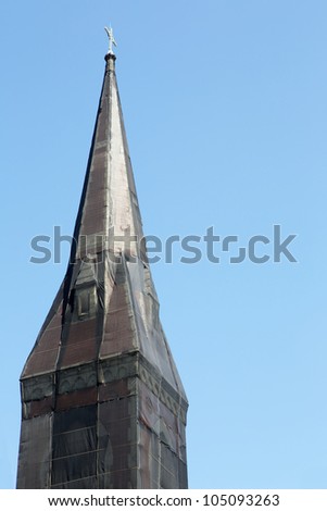Curious black net shrouded christian church steeple against blue sky