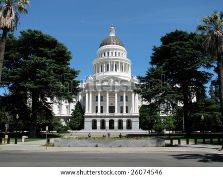 California State Capital in Sacramento on a perfect da with green trees and blue sky framing the white building