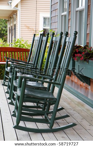 Four green wooden rocking chairs on a porch with partial wood swing 