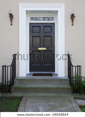 White wood bordered black door of beige stucco house