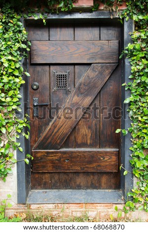 Small Spanish style dark stained wood door to secret garden with grated window