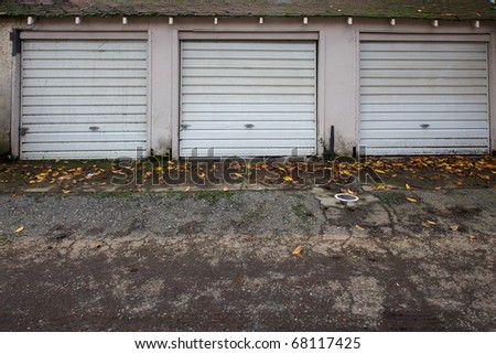 Three old white metal garage doors in autumn