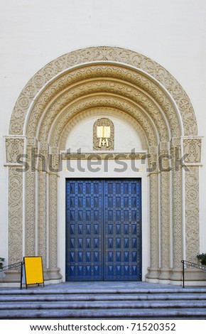 Ornate Blue Church door with molded trim facade and yellow blank sign