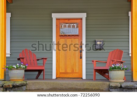 Mission style Stained wood front door with beveled glass surrounded by two Adirondack chairs and flowers
