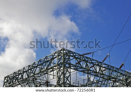 Green steel electrical power substation against blue sky and white clouds