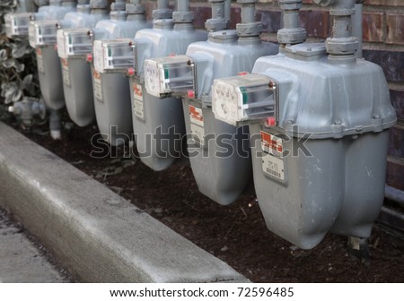 Row gray gas meters at an apartment complex done with a narrow field of focus without manifold