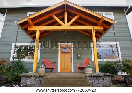 Mission style Stained wood front door with beveled glass surrounded by two Adirondack chairs and flowers