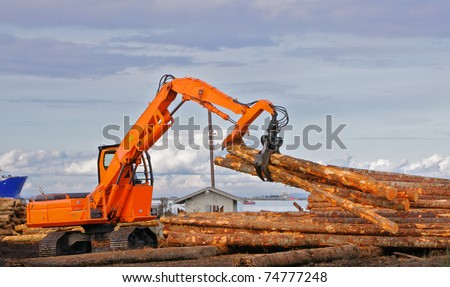 Heavy duty orange claw like logging machine for picking up and piling logs with river and ship in background