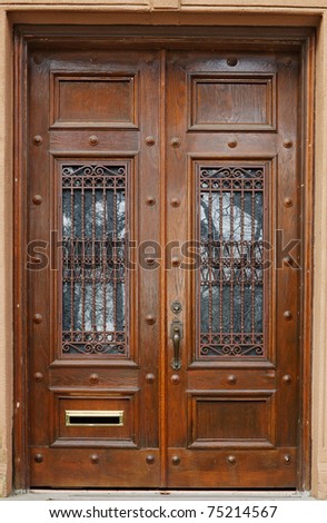 Old brown stained doors with ornate security bars over glass windows