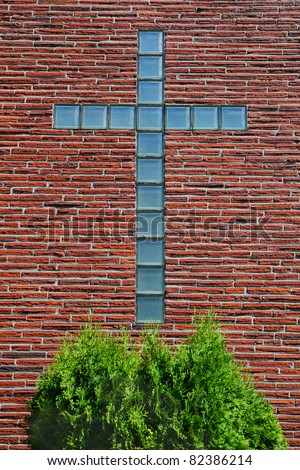 Blue glass brick or block cross on a thin red brick wall of a church