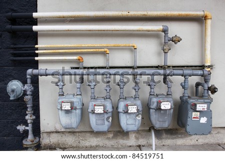 Five gray gas meters against a black and white wall