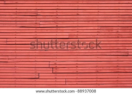 Old wood slat wall painted red with vertical nail holes