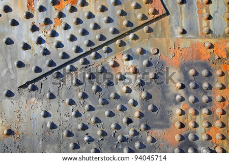 Old rusty rivets on large corroding steel plates of a train and auto Bridge