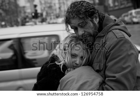 Black and white image of homeless couple embracing in city center