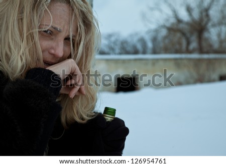 Portrait of frozen homeless woman holding a bottle of alcohol
