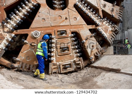 Construction worker looking at tunnel boring machine cutter head
