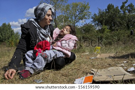 SOFIA, BULGARIA, 20 SEPTEMBER 2013 - Unknown Syrian mother, holding her sick child is sitting on the grass near a refugee camp in Sofia, Bulgaria.