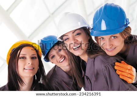 Young female construction workers with protective clothes and helmets. Isolated with work path.