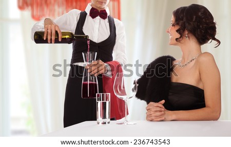 Waitress serving wine to a smiling lady guest. Isolated with work path