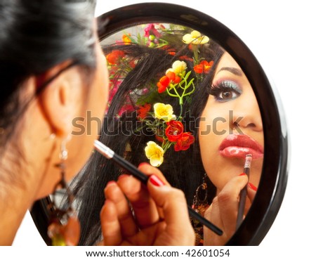 reflection in a mirror of a beautiful hispanic female applying lipstick