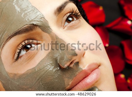 stock photo closeup of a young woman face half with clay mask
