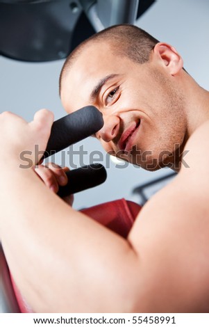 Close-up of an attractive male working out at the gym, looking at the camera