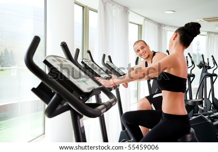 Athletic couple on veloargometers in gym, having fun