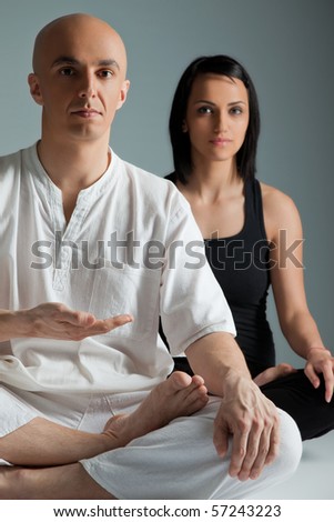 Man in white and woman in black doing yoga exercise, meditation