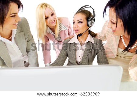 Four beautiful successful businesswomen talking behind laptop, one of them with headset