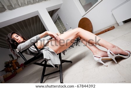 Beautiful female model leaning on a chair backstage, looking tired