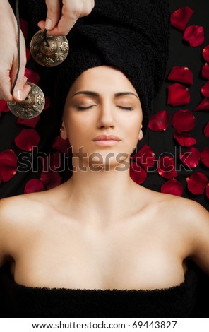Beautiful female receiving energy sound massage in spa, eyes closed