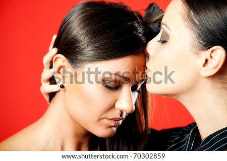 two beautiful females, one kissing the forehead of the other