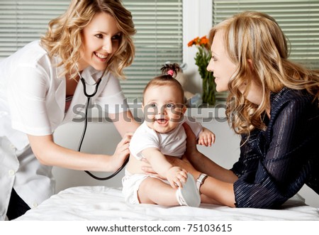Female doctor examining little smiling baby girl, held by mother