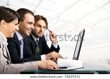 Team of three businesspeople sitting behind laptop, looking at the laptop, copyspace
