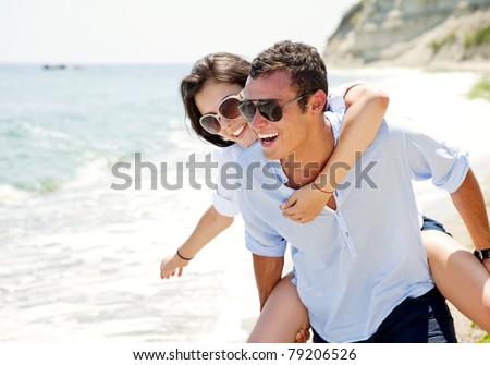 Happy young couple enjoying a solitary beach backriding