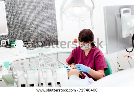 Female dentist working on patient in modern equipped cabinet