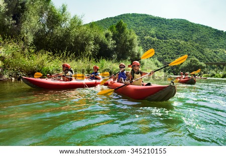 Several two people team inflatable canoes rafting in a calm waters with beautiful surrounding.