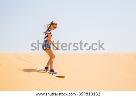 Lonely girl learning to sand boarding in a desert down the dunes