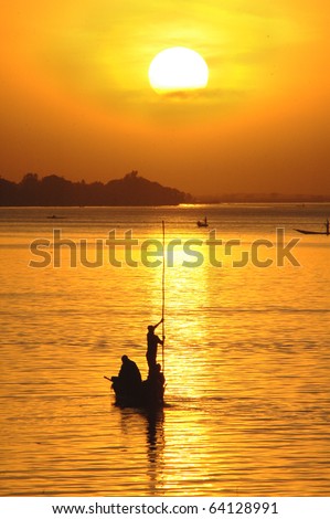Vertical silhouette of African fisherman in canoe at sunset