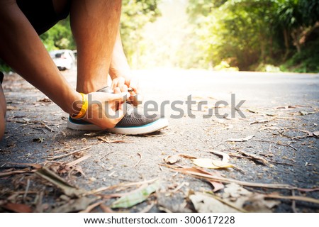 Barefoot running shoes closeup. man athlete tying laces for jogging on road in minimalistic barefoot running shoes. Runner getting ready for training. Sport lifestyle.
