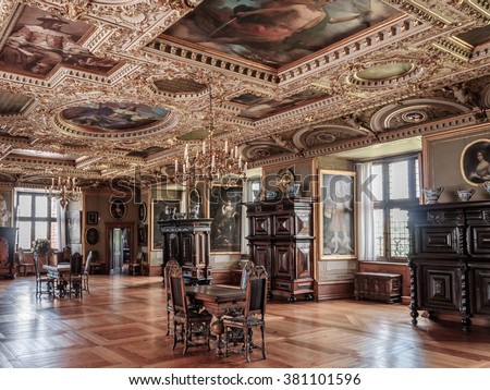HILLEROD, DENMARK - 2014 JUN 08: Interior (One of the rooms of Frederiksborg Castle). Room with wooden parquet floors, a fireplace, and several antique tables. The ceiling with paintings and stucco.
