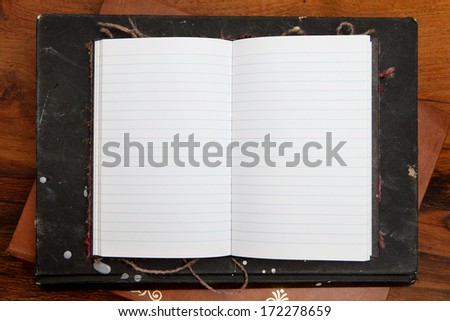 Open notebook on wooden table. Lined paper background.