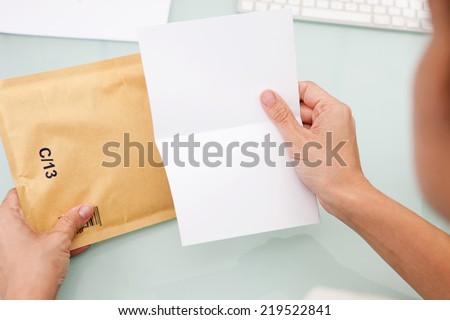 Woman reading letter. Blank card and envelope over grey background