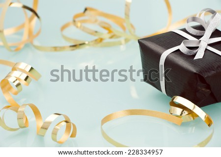 Black gift box with silver bow on light background.
