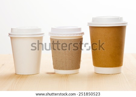 Disposable coffee cups on wooden table.
